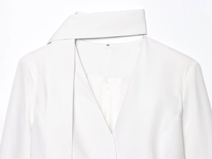 Detail of white V-neck blazer collar with matching tie belt and size M label