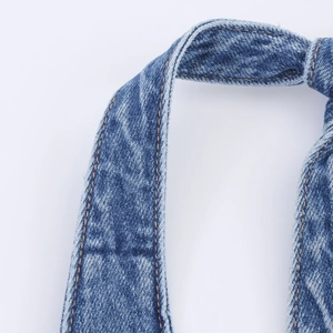 Detailed close-up of halter denim dress with orange contrast stitching and knotted fabric