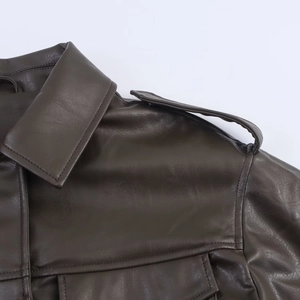 Close-up detail of dark brown faux leather jacket with shoulder epaulettes and pocket flap