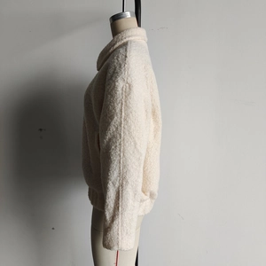 Close-up of beige teddy jacket fabric showing high-density fleece texture and stand collar