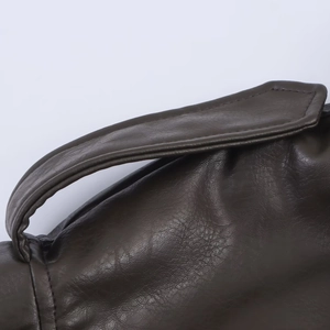 Detailed close-up of dark brown faux leather texture with fine stitching on shoulder strap