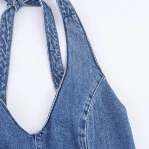 Detailed close-up of dark blue halter V-neckline and stitching on denim dress