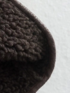 Close-up of thick dark brown faux shearling lining for winter coat insulation