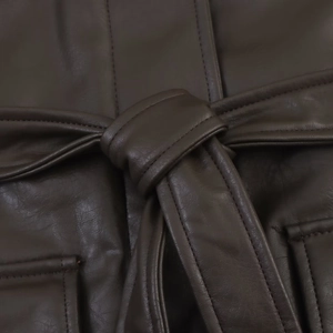 Detail of dark brown faux leather jacket featuring waist tie belt and stitching