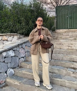Detailed outdoor shot of a brown textured wool jacket with a stylish beige trousers look