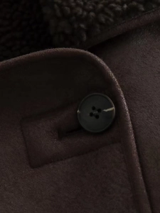 Macro detail of dark brown faux suede coat with black button and soft shearling lining
