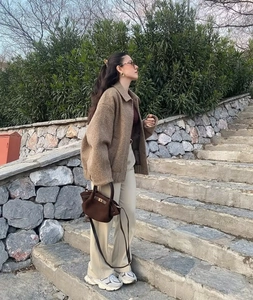 Outdoor street style view of brown wool jacket paired with beige wide-leg trousers