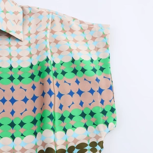 Detail of vintage geometric print on satin shirt showing precise stitching and vibrant colors