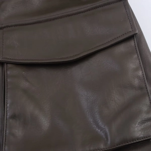 Detail of dark brown faux leather jacket featuring a classic flap pocket and fine stitching