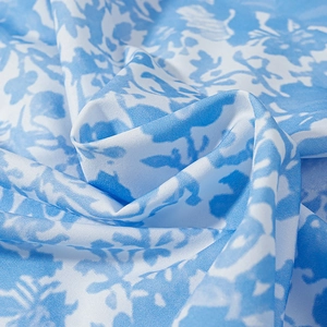 Vue rapprochée du tissu à motif floral bleu et blanc au drapé souple et texture de soie