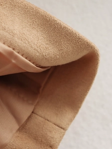 Detail of tan suede fabric featuring smooth satin lining and precise stitching on the jacket