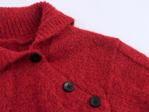 Detail of red cable knit sweater showing textured fabric, collar and black buttons