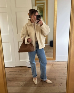Chic cream wool-look jacket styled with blue straight jeans and tan leather handbag
