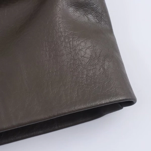 Close-up of deep brown pebbled faux leather texture on the vintage biker jacket