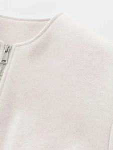 Nahaufnahme der weißen Kurzjacke mit wollartiger Textur und silbernem Reißverschluss