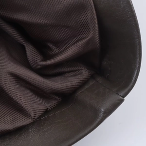 Close-up of faux leather texture and twill lining on a dark brown biker jacket