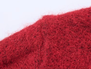 Close-up of red cable knit sweater featuring fuzzy mohair texture and raw edge detailing