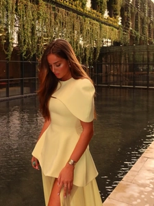 Détail d'une robe crème élégante avec volant asymétrique et fente latérale haute