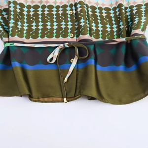Detailed view of satin shirt with geometric print, gold buttons and drawstring waist