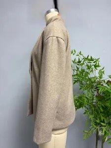 Detail view of the side cut and wool fabric texture of the beige short coat jacket