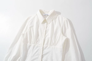 Détail de la chemise blanche à manches longues avec broderie florale et taille plissée
