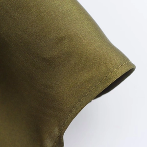 Detailed close-up of olive green satin shirt cuff with fine stitching and silky texture
