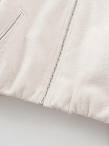 Detail der hellgrauen Bomberjacke mit glattem Metallreißverschluss und elastischem Rippsaum