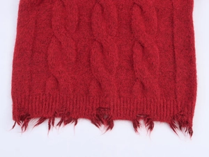 Detail shot of a bright red cable knit sweater featuring a distressed frayed hem finish