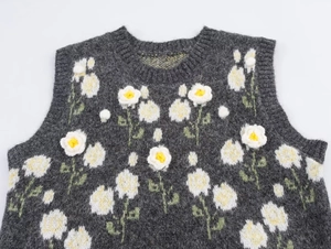 Dettaglio del motivo floreale 3D su un gilet in maglia grigio scuro con trama di lana