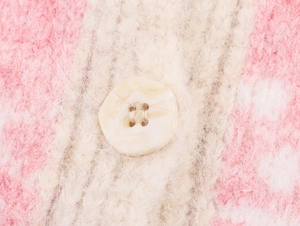 Close-up of pink and white striped knit vest with marble pattern button detail