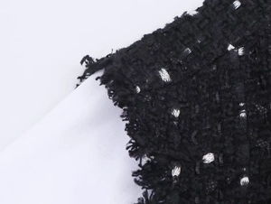 Detailansicht der schwarzen Tweed-Stoffstruktur mit Fransenrand und weißen Akzenten