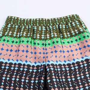 Detailed macro view of high-waist elastic waistband on geometric print satin trousers