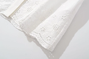 Détail de la broderie tournesol ajourée blanche et coutures fines sur chemise femme