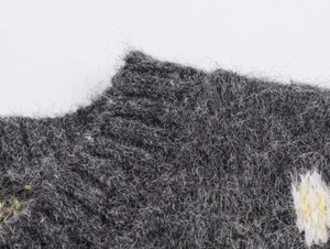 Dettaglio ravvicinato del gilet in maglia grigio scuro con tessuto morbido e ricami floreali