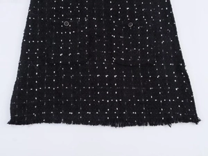 Detail von Tweed-Stoff mit Fransen Saum und Zierknöpfen auf einem Mini-Kleid