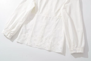 Détail de chemise blanche en coton avec broderie florale complexe et ourlet ajouré chic