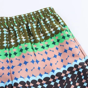 Detail view of elastic waistband on satin trousers with colorful geometric prints
