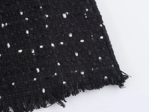 Nahaufnahme der schwarzen Tweed-Struktur mit Fransenrand und weißen Webdetails