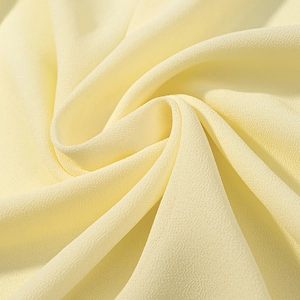 Gros plan d'un tissu mousseline jaune crème doux avec texture délicate et plis en spirale