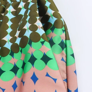 Macro shot of satin fabric featuring olive green and blue geometric star patterns