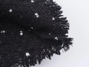 Makroansicht der schwarz-weißen Tweed-Struktur mit dekorativen Fransen-Details
