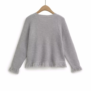 Women's grey knit cardigan sweater featuring fringed hem and decorative button details