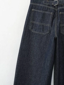 Details der Vintage-Metallschnalle und gelbe Kontrastnähte an der Jeanshose