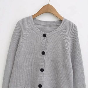Light gray knit cardigan with black decorative buttons and round neck on wooden hanger