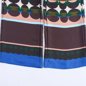 Detail of satin wide-leg trousers featuring colorful geometric patterns and silky texture
