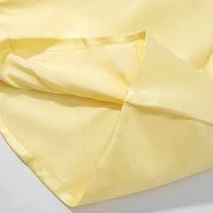 Gros plan détaillé de l'ourlet en satin jaune clair lisse avec coutures de qualité