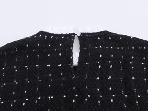 Detail eines Tweedkleides mit weißem Spitzen-Rüschenkragen und Knopfverschluss