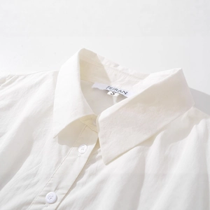 Détail du col de chemise blanche brodée avec boutons et manches longues élégantes