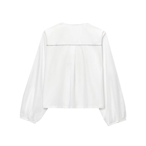 Detail of white lantern sleeve blouse featuring black zigzag back stitching and center pleat