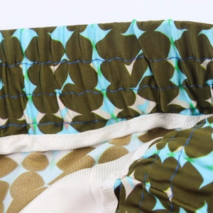 Detail of elastic waist with blue double stitching on geometric floral satin pants